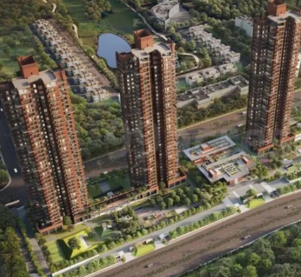 Aerial drone rendering of the premium residential complex showcasing three brick-red skyscraper towers surrounded by lush greenery and a water body
