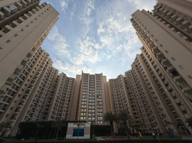 Low-angle view looking up at the multi-story residential towers surrounding the central courtyard at Oasis Grandstand under a blue sky